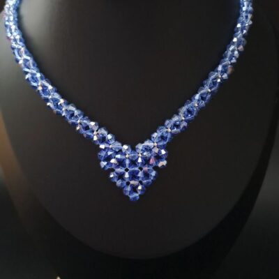 Elegancki naszyjnik z błękitnych kryształków w kształcie litery V, przyciągający uwagę blaskiem i głębokim kolorem. Delikatne srebrne akcenty dodają wyrafinowania, czyniąc go idealnym wyborem do klasycznych i współczesnych stylizacji.