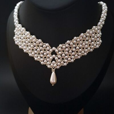 Elegancki naszyjnik na ślub – wykonany z pereł i delikatnych koralików w srebrzysto-złotych odcieniach. Geometryczna forma podkreśla szyję, nadając stylizacji nowoczesny i zmysłowy charakter, idealny na wyjątkowe okazje.