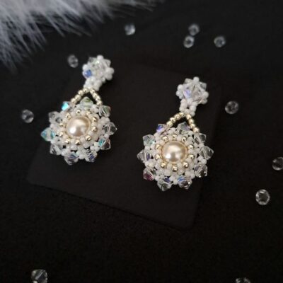 Stylowe kolczyki na ślub, ozdobione połyskującymi kryształkami, które dodają luksusu i przyciągają wzrok. Wyjątkowy dodatek do ślubnej kreacji, idealny dla panny młodej o klasycznym lub romantycznym stylu.