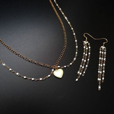 Elegancki zestaw biżuterii z masą perłową – dwurzędowy naszyjnik z sercem i subtelne wiszące kolczyki. Złota stal chirurgiczna i perłowe detale sprawdzą się jako romantyczny dodatek na co dzień i wyjątkowe okazje. Idealny pomysł na prezent.
