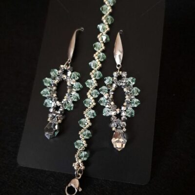 Srebrny komplet biżuterii z kolczykami i delikatną bransoletką z kryształków Preciosa Bicone w odcieniu chrysolite, uzupełniony jasnymi labrador half i srebrnymi koralikami Miyuki. Biżuteria ręcznie wykonana, lekka i błyszcząca, idealna na śluby i eleganckie wydarzenia. Komplet dopasowany kolorystycznie i spójny stylistycznie.