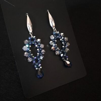 Ręcznie wykonane kolczyki wieczorowe z granatowych kryształków Montana AB i błyszczących Vitrail Light, z dodatkiem srebrnych koralików i srebrnych bigli. Idealny model do sukienek koktajlowych, stylizacji na wesele lub uroczystości dzięki intensywnemu, świetlistemu połyskowi. Kolczyki są lekkie, trwałe i eleganckie.