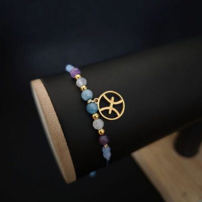 Jasna bransoletka zodiakalna Ryby wykonana z ametystu, akwamarynu i kamienia księżycowego, z przekładkami Miyuki Delica. Regulowany sznurek makramowy zapewnia wygodne noszenie. Biżuteria o lekkim, eterycznym charakterze.