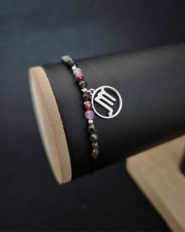 Bransoletka z kamieni naturalnych dla Skorpiona wykonana z ametystu, obsydianu i granatu, z metalowymi przekładkami i zawieszką znaku. Regulowany czarny sznurek makramowy zapewnia komfort noszenia. Biżuteria zodiakalna o ciemnej, intensywnej kolorystyce.