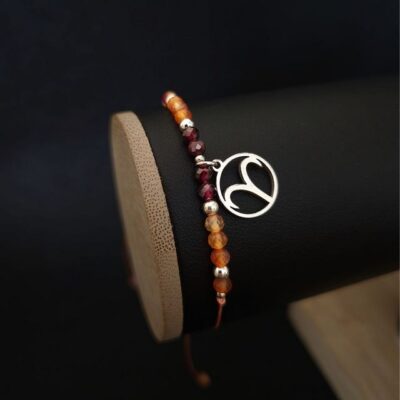 Bransoletka z kamieni naturalnych dla znaku Barana, wykonana z karneolu, granatu i hematytu, ozdobiona zawieszką ze stali nierdzewnej z symbolem zodiaku. Regulowany sznurek makramowy zapewnia wygodne dopasowanie do nadgarstka. Stylowa biżuteria zodiakalna o silnej, energetycznej symbolice.
