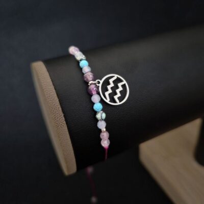 Bransoletka Wodnik wykonana ręcznie z akwamarynu, ametystu i turkusu, na regulowanym fioletowym sznurku makramowym. Zawieszka z symbolem Wodnika nadaje jej indywidualny charakter. Idealna jako prezent urodzinowy lub talizman wolności.