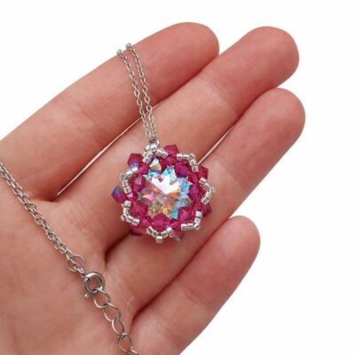 Elegancki naszyjnik z kryształami Preciosa Crystal AB i Fuchsia AB oraz srebrnymi koralikami Miyuki. Centralny Rivoli Maxima 18 mm mieni się wielobarwnymi refleksami, a ręcznie wyplatana zawieszka ma około 2,9 × 2,7 cm.