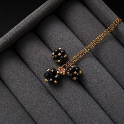 Czarno-złoty komplet biżuterii handmade z naturalnym turmalinem, składający się z minimalistycznych kolczyków sztyftów i naszyjnika z zawieszką. Czarny turmalin kojarzony jest z ochroną energetyczną, wewnętrzną równowagą, uziemieniem oraz poczuciem stabilności.
