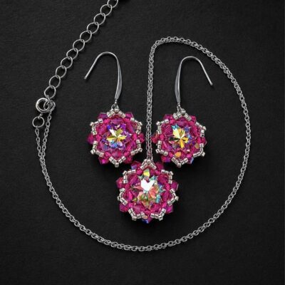 Komplet biżuterii handmade z kryształami Preciosa Crystal AB i Fuchsia AB, składający się z wiszących kolczyków oraz naszyjnika z dużą kryształową zawieszką. Opalizujące Rivoli Maxima, różowe kryształki Bicone, srebrne koraliki Miyuki i stal chirurgiczna tworzą elegancką biżuterię na specjalne okazje.