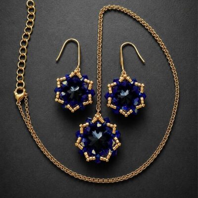 Komplet biżuterii handmade Cobalt Maxima z czarnymi kryształami Preciosa Rivoli Maxima Jet i niebieskimi kryształkami Bicone Cobalt AB. Wiszące kolczyki o długości 4 cm oraz naszyjnik z zawieszką około 2,7 × 2,9 cm zdobią złote koraliki Miyuki Delica i elementy ze stali nierdzewnej.