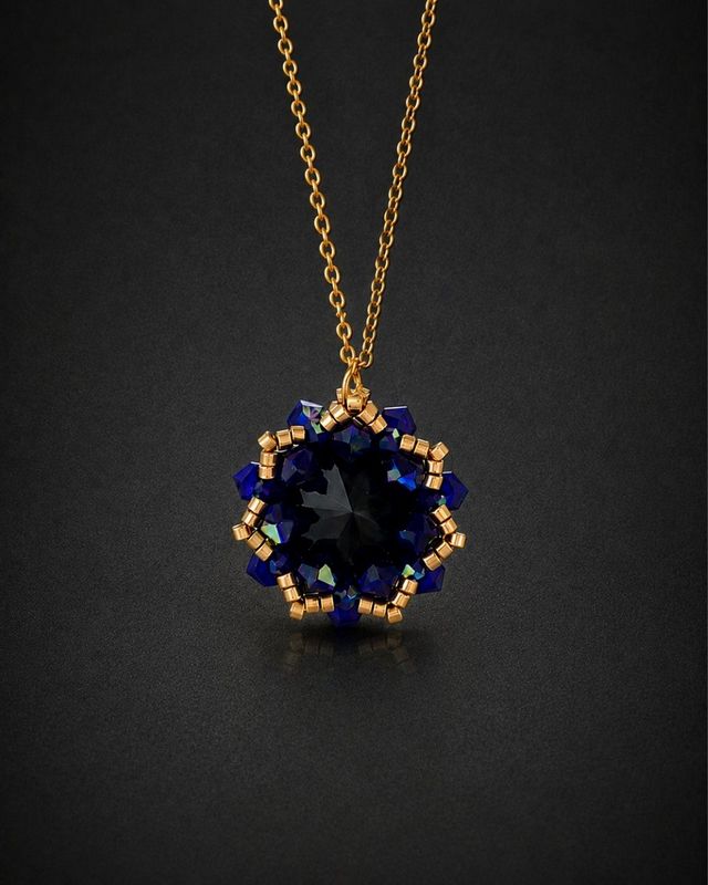 Elegancki złoty naszyjnik na wesele Cobalt Maxima z czarnym kryształem Preciosa Rivoli Maxima Jet i kobaltowymi kryształkami Bicone Cobalt AB. Ręcznie wykonana zawieszka około 2,7 × 2,9 cm z opalizującymi refleksami błękitu i fioletu na łańcuszku ze stali nierdzewnej.