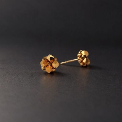 Minimalistyczne złote kolczyki sztyfty z kryształami Preciosa Crystal Aurum o lustrzanym, metalicznym wykończeniu. Ręcznie wyplatane kryształki Bicone 4 mm ze złotymi koralikami Miyuki Delica tworzą niewielkie kolczyki ze stali nierdzewnej o średnicy około 7 mm.