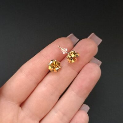 Minimalistyczne złote sztyfty Preciosa – eleganckie kolczyki z kryształami Złote kolczyki sztyfty z czeskich kryształów Preciosa Bicone Crystal Aurum i koralików Miyuki Delica. Drobne kolczyki handmade o średnicy 0,7 cm z fasetowanymi kryształami o metalicznym połysku, złotą bazą ze stali nierdzewnej i przestrzenną formą.