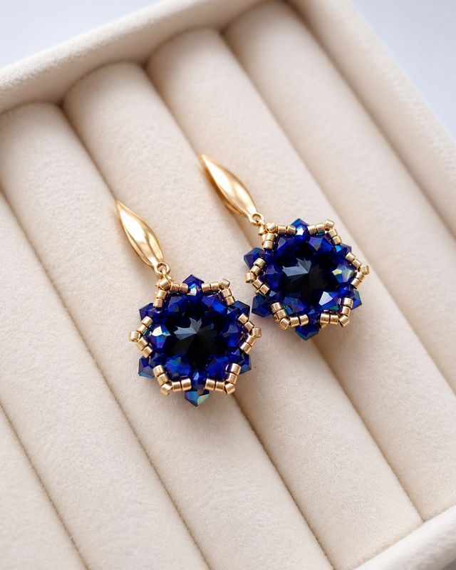 Czarno-niebieskie kolczyki handmade z kryształami Preciosa Jet i Cobalt AB o intensywnym, opalizującym połysku. Wiszące kolczyki ze złotymi dodatkami Miyuki Delica, wykonane ze stali nierdzewnej, mają długość około 4 cm i szerokość 2 cm.